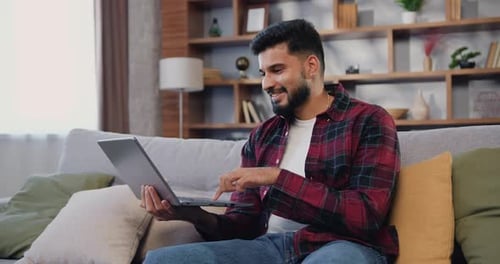 Young Man Using Laptop on Comfortable Couch