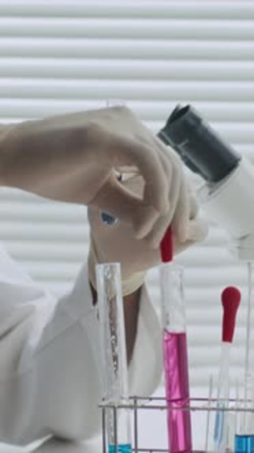 Scientifique méconnaissable ajoutant un agent chimique rose
