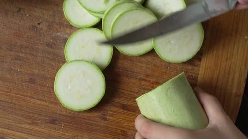 Cutting fresh zucchini on a wooden cutting board