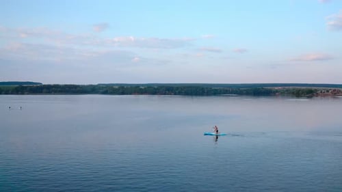 Man Paddleboarding on a Serene Lake