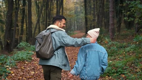 Rear view of couple spending time together walking in forest at morning.