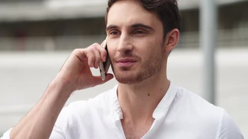 Happy businessman having mobile phone talk outside in modern city