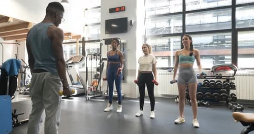 Instructor Giving a Fitness Class Using Dumbbells at Modern Gym