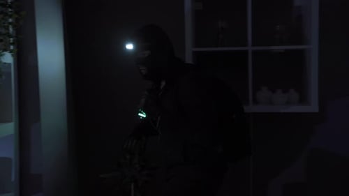 Hooded Figure with Flashlight Searching Dark House
