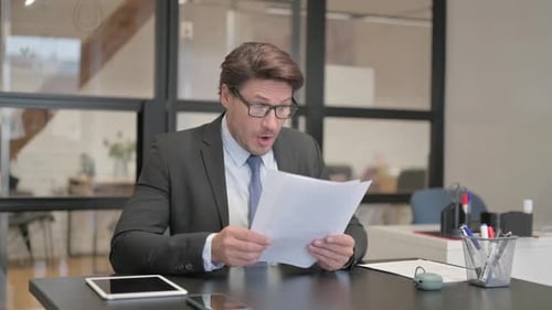 Middle Aged Businessman Feeling Upset while Reading Contract in Office