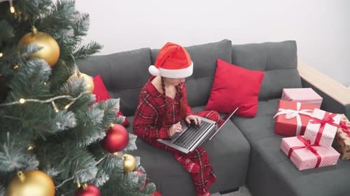 Girl in a Santa Claus Hat Communicates with Her Family and Friends on the Computer