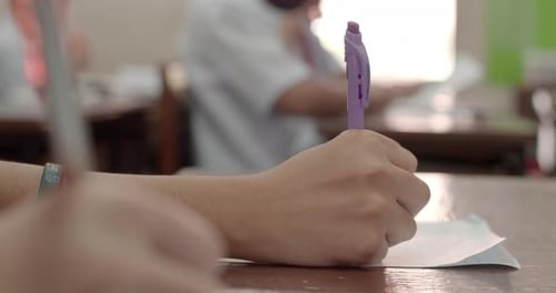 Students Writing at Desks During Exam in Classroom