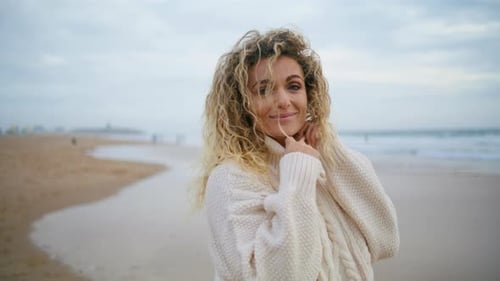 Woman Posing Autumn Beach in Warm Sweater. Carefree Blonde Enjoying Ocean Shore