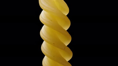 Eine einzelne Fusilli-Nudeln dreht sich auf schwarzem Grund, während ich andere Nudeln aus der Handfläche gieße