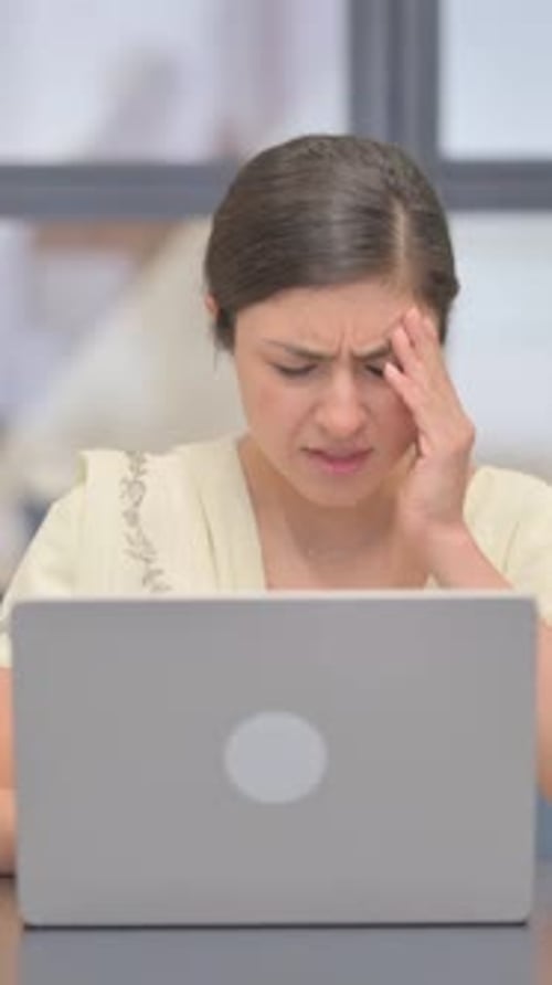 Woman with Headache Uses Laptop in Office