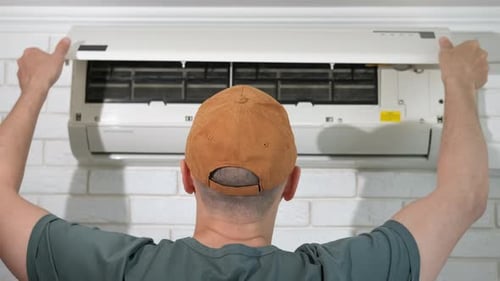Man Closing Air Conditioner Panel Using Remote Control