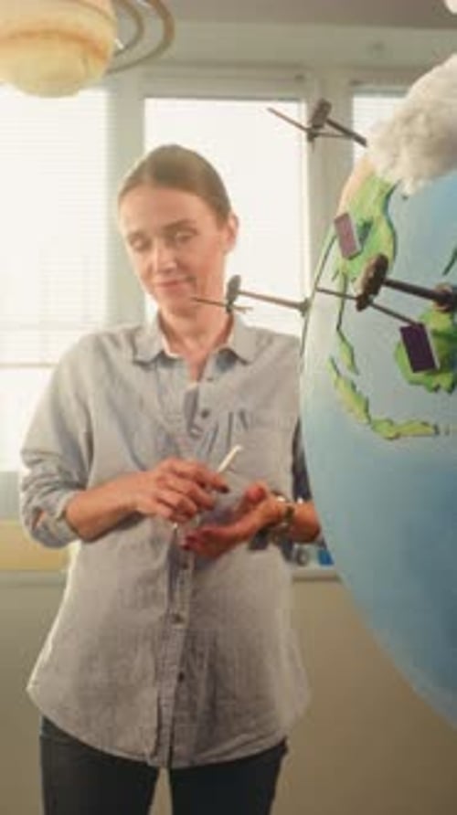 Boy Presenting Renewable Energy Sources Using Globe with 3D Models of Wind Turbines and Solar Panels