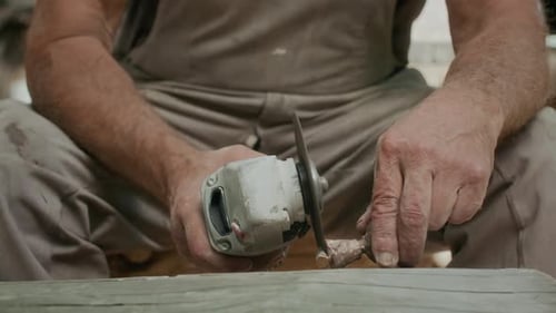 Male Sculptor Carving Stone Piece with Angle Grinder