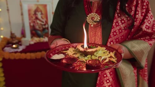 Woman Holds Plate with Lit Oil Lamp