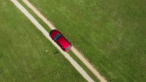 A car drives through the ruts of a dusty dirt road across wild deserts fields.