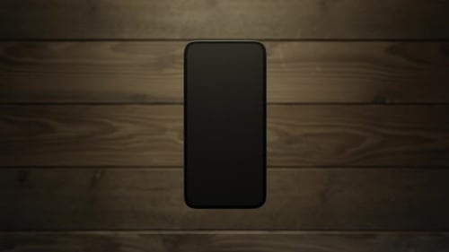 The phone rises above the wooden surface showing the display.