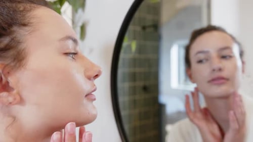 Looking In Mirror Woman Touching Face And Examini