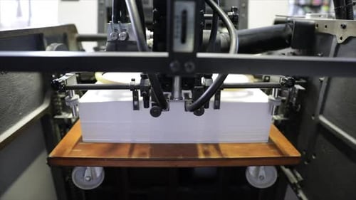 Industrial printer uploads white sheets of paper, close up view