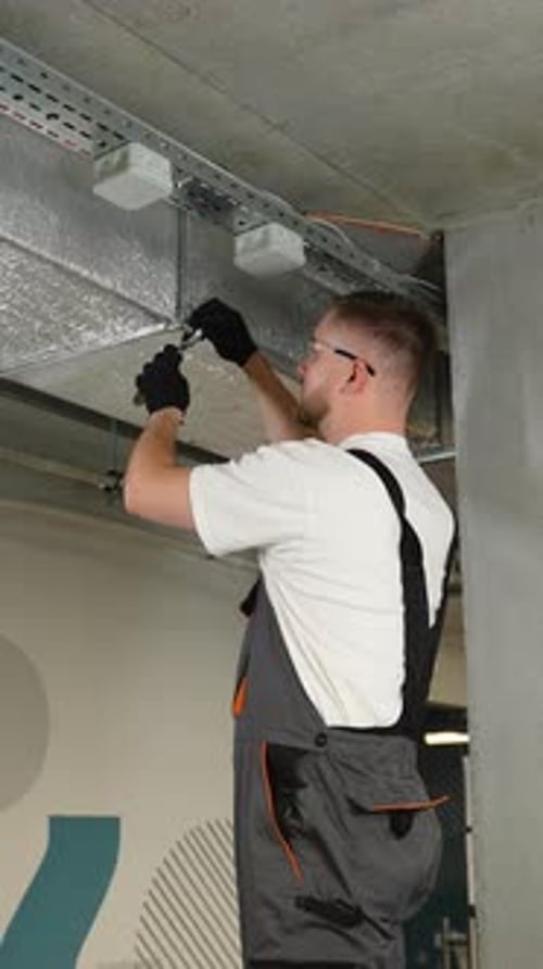 Construction Worker Installing Electrical Fixtures on Ceiling Indoors