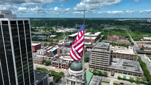 American flag waving above downtown Fort Wayne, Indiana. Aerial establishing shot of USA city with A