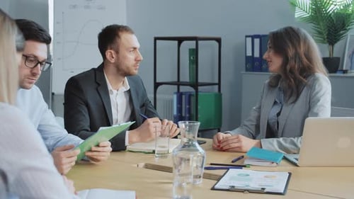 Footage of Four Caucasian People Sitting at Negotiating Table Talking End of Business Meeting Man