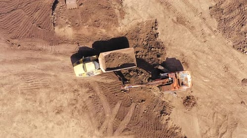 Excavator Loads Dump Truck with Soil from Above