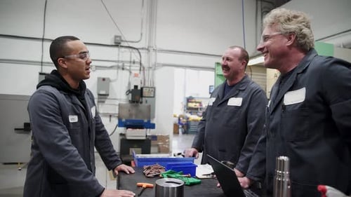 Men Discussing Work in Factory Wearing Safety Glasses