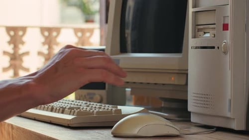 Hombre trabajando y jugando en una computadora retro, ingeniero de TI con una computadora antigua en casa usando una vieja