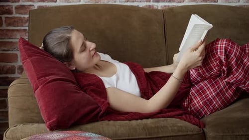 Woman Reading a Book on Brown Couch