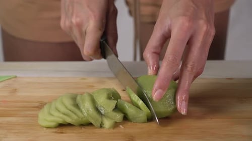Slicing a Fresh Kiwi on Wooden Board