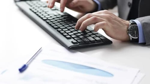 Businessman hands typing on computer keyboard in bright modern office workplace