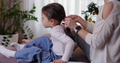 Caring Mother Braiding Her Little Daughter's Hair