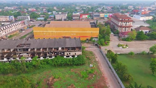 Aerial view of old industrial building near town with overgrown land