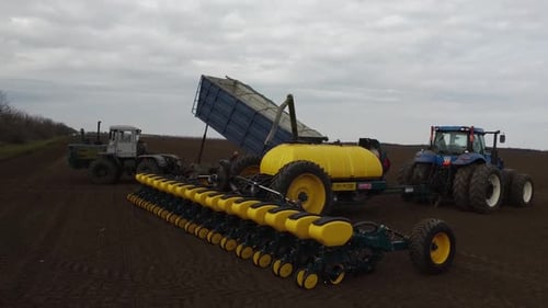 Blue tractor with yellow seeder working on the field in Ukraine OA