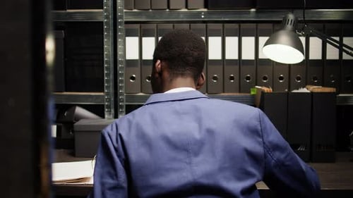 Adult Works in a Dark File Storage Office