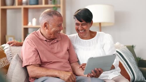 Elderly Couple Laughing Looking at Tablet at Home