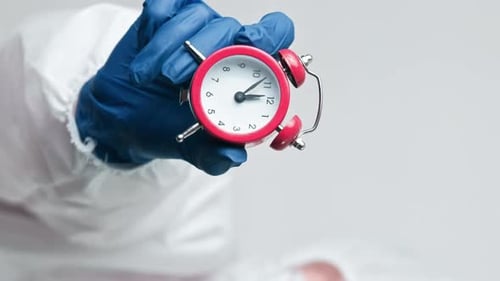 Alarm Clock Held by Person in Protective Suit