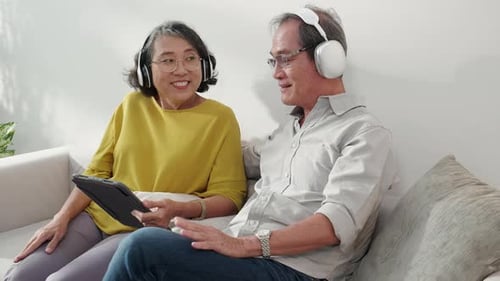 Senior Couple Relaxing with Tablet and Headphones at Home