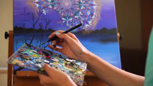 Talentierte Malerin kreiert ein Bild mit Palette und Leinwand