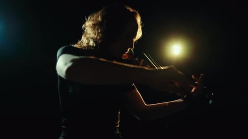Female Violinist Plays Violin in Darkly Lit Scene