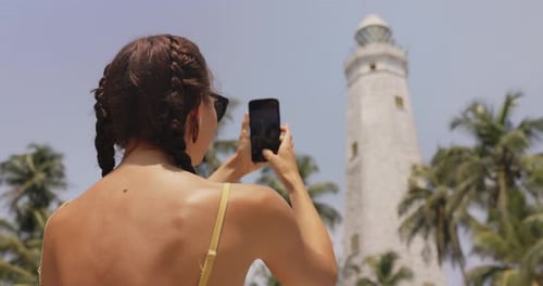 Woman Traveler in Front of Famous Landmark of Sri Lanka with Smartphone Dondra Lighthouse