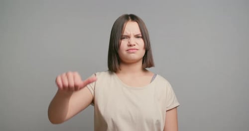 Unsatisfied Latin Teenager Girl Hands Fingers Demonstrate Thumbs Down Isolated on Gray Color
