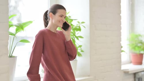Woman Talking on Smartphone by Window