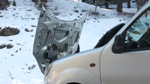 Man Repairs Car in Snowy Wilderness in Winter