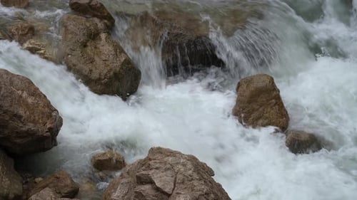 Intense water splash on river stones with a stunning mountain valley background for outdoor