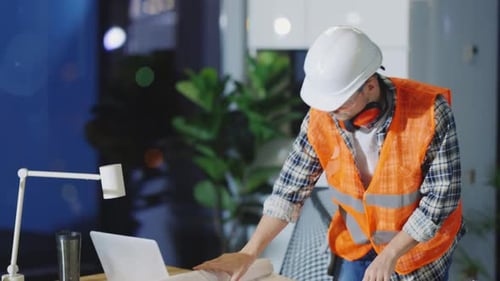 Caucasian Handsome Young Engineer Sitting at Table and Learning Building Plan for New Construction