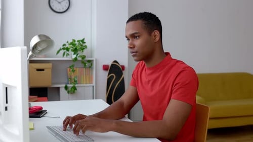 Young Adult Typing on Computer in Bright Room
