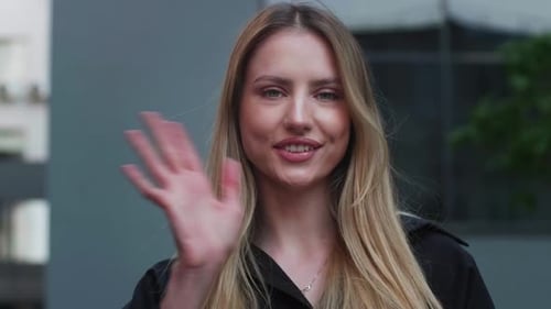 Woman Smiling and Waving Hello in City