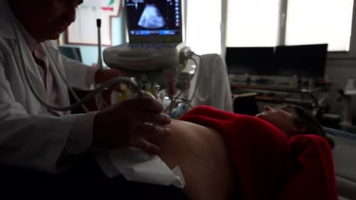 Gynecologist applying gel to pregnant woman's belly in ultrasound scan
