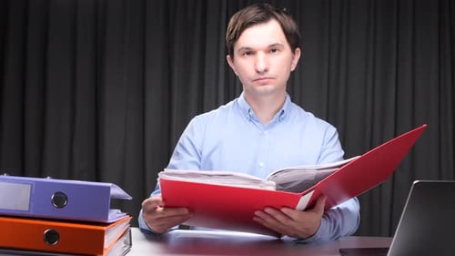 Office Worker Reading Documents in a Red Folder at Night